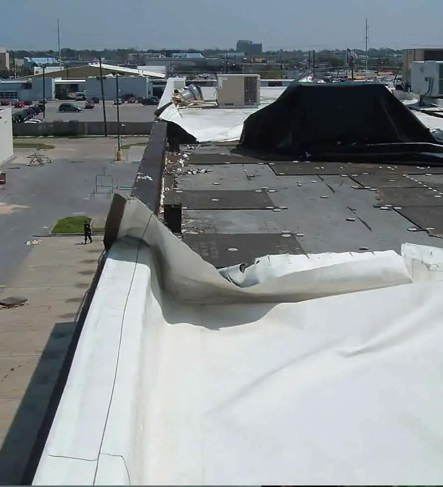 Wind-damaged membrane at a commercial roof edge
